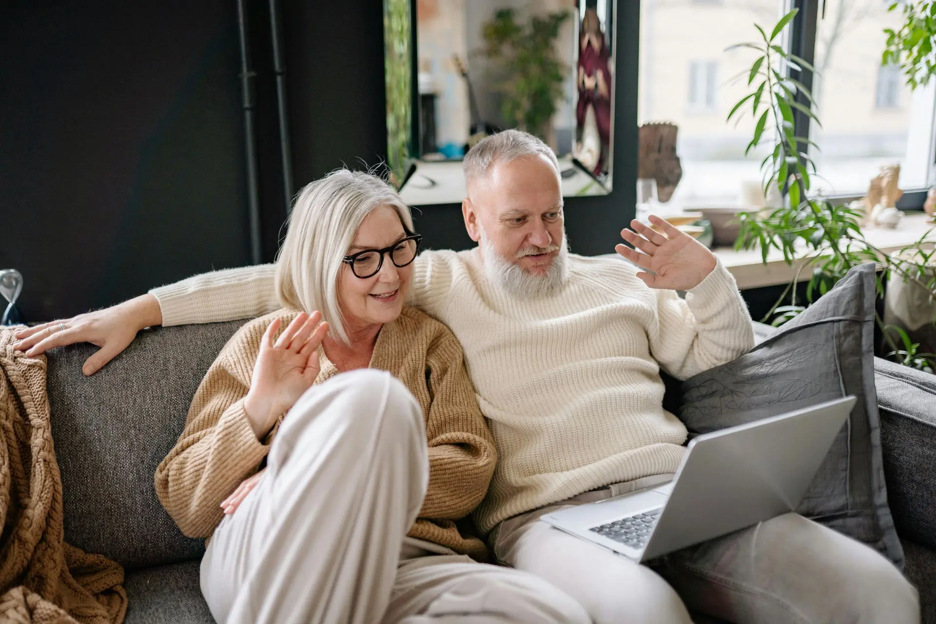 Elderly couple enjoying time together on a couch with a laptop.